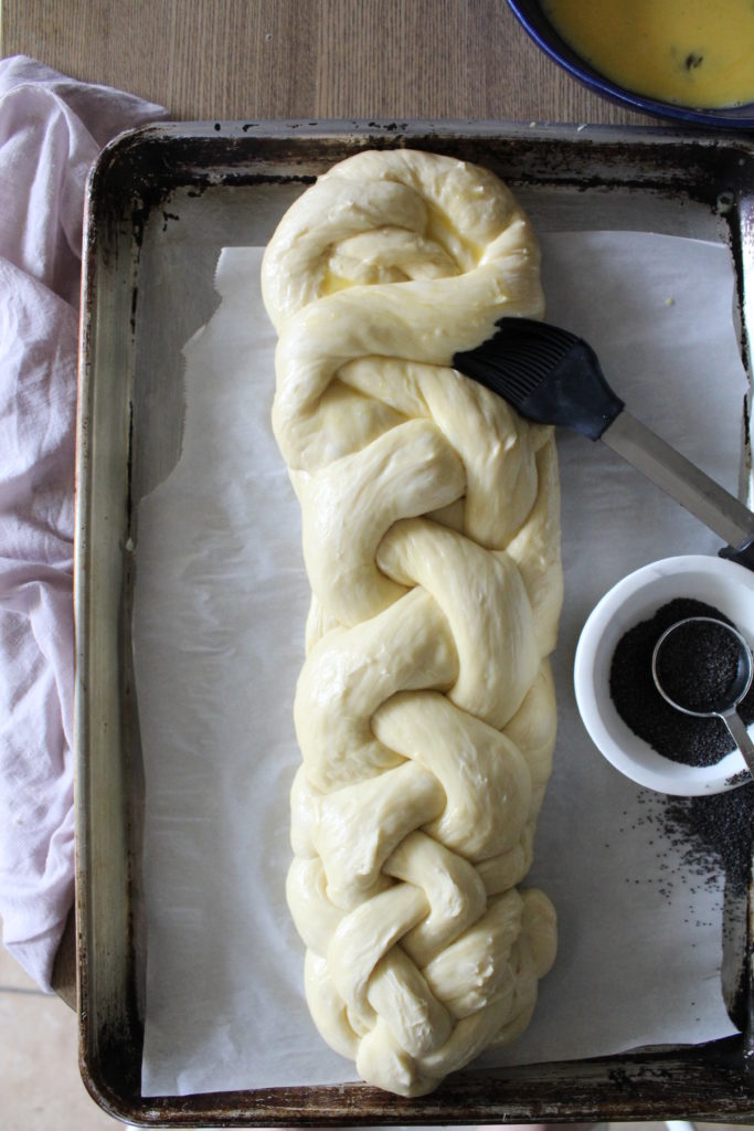 challah loaf raw being brushed with egg wash