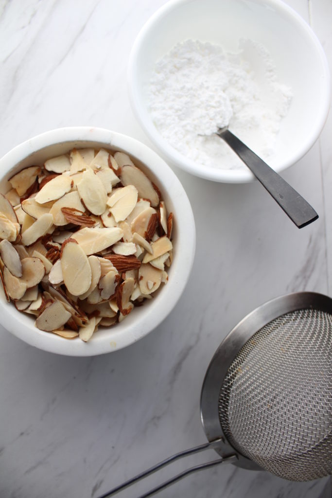 slivered almonds in a bowl nex to a bowl of powdered sugar