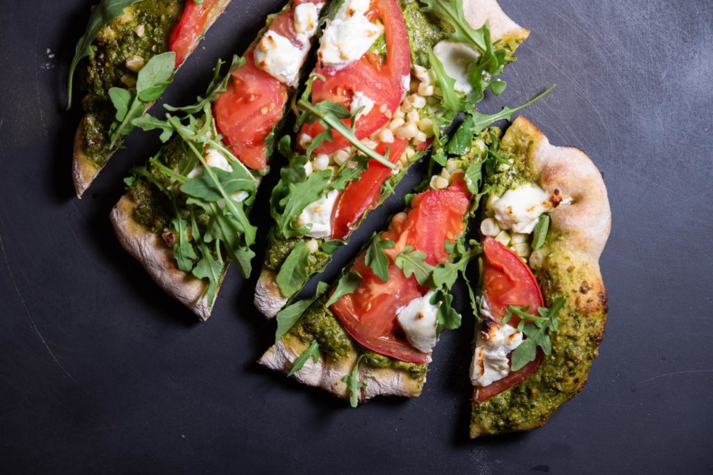 grilled flatbread with goat cheese, tomato, arugula, corn and pesto toppings