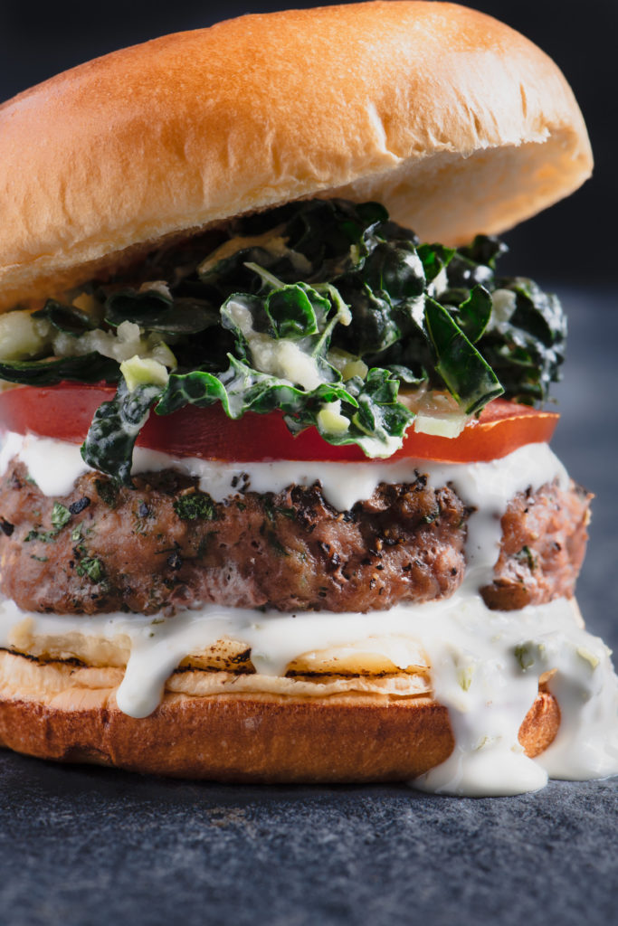 grilled turkey burger with jalapeno lemon aioli, tomato, and kale coleslaw on a brioche bun