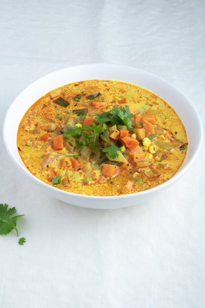 turmeric soup with yam, poblano, corn, coconut milk in bowl