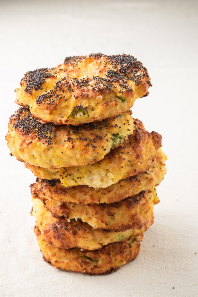 tall stack of cauliflower bagels with jalapeno and cheddar cheese with a poppy seed garnish