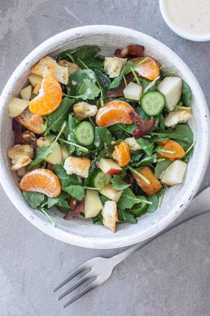 kale salad with apple, mandarin, bacon, and croutons with champagne dressing