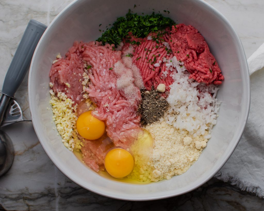 ground pork and beef, eggs, almond flour, onion, garlic, and parsley in a bowl
